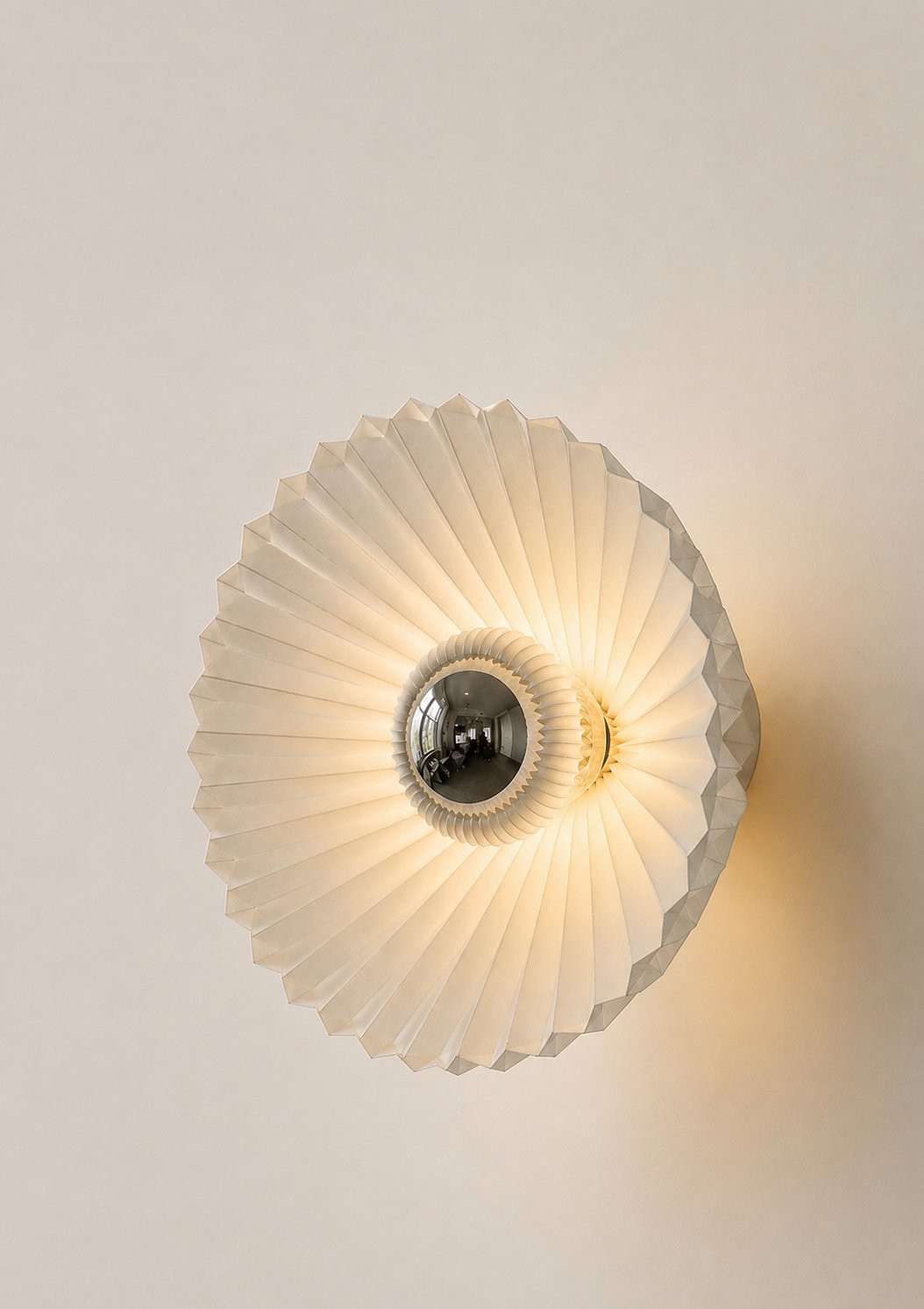 Cone-shaped pleated wall lamp with mirrored centre, glowing