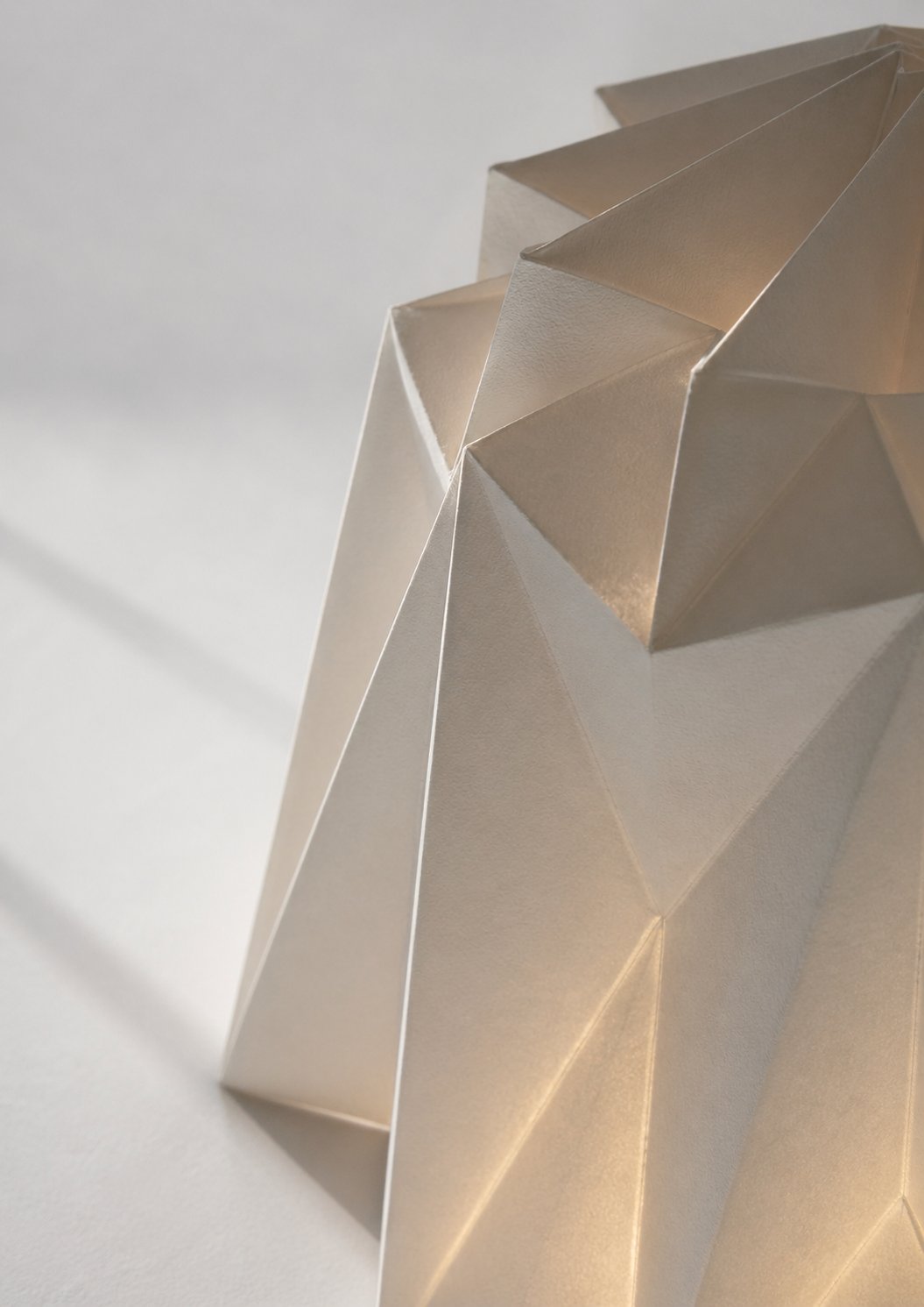 Close-up of a faceted geometric pleated paper form, backlit